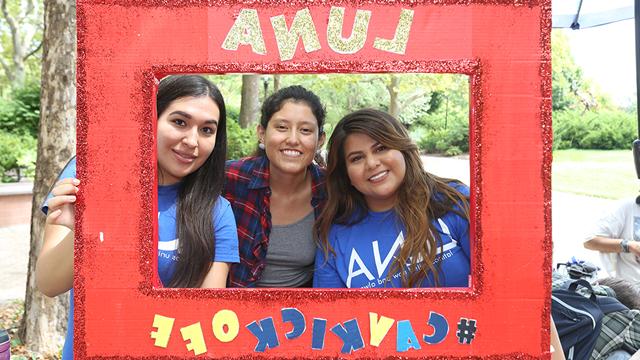 Three Hispanic students posing with a LUNA poster during Cav Kickoff